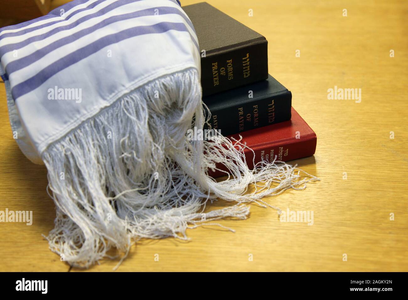 A Jewish shawl 'Tallit' lays over a pile of Jewish prayer books on a table Stock Photo