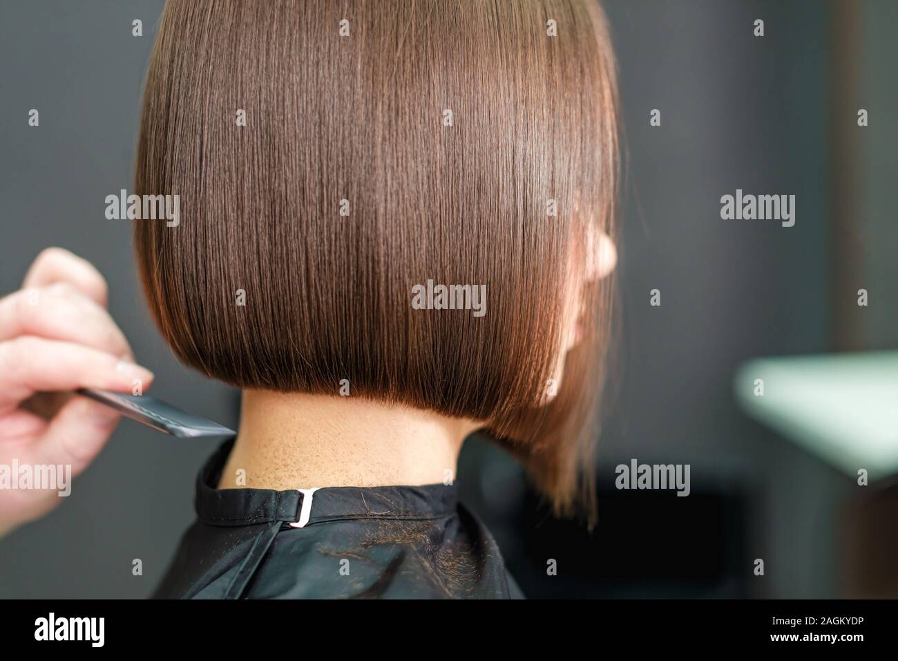 Hairdresser combs woman's short hair with comb, close up, copy