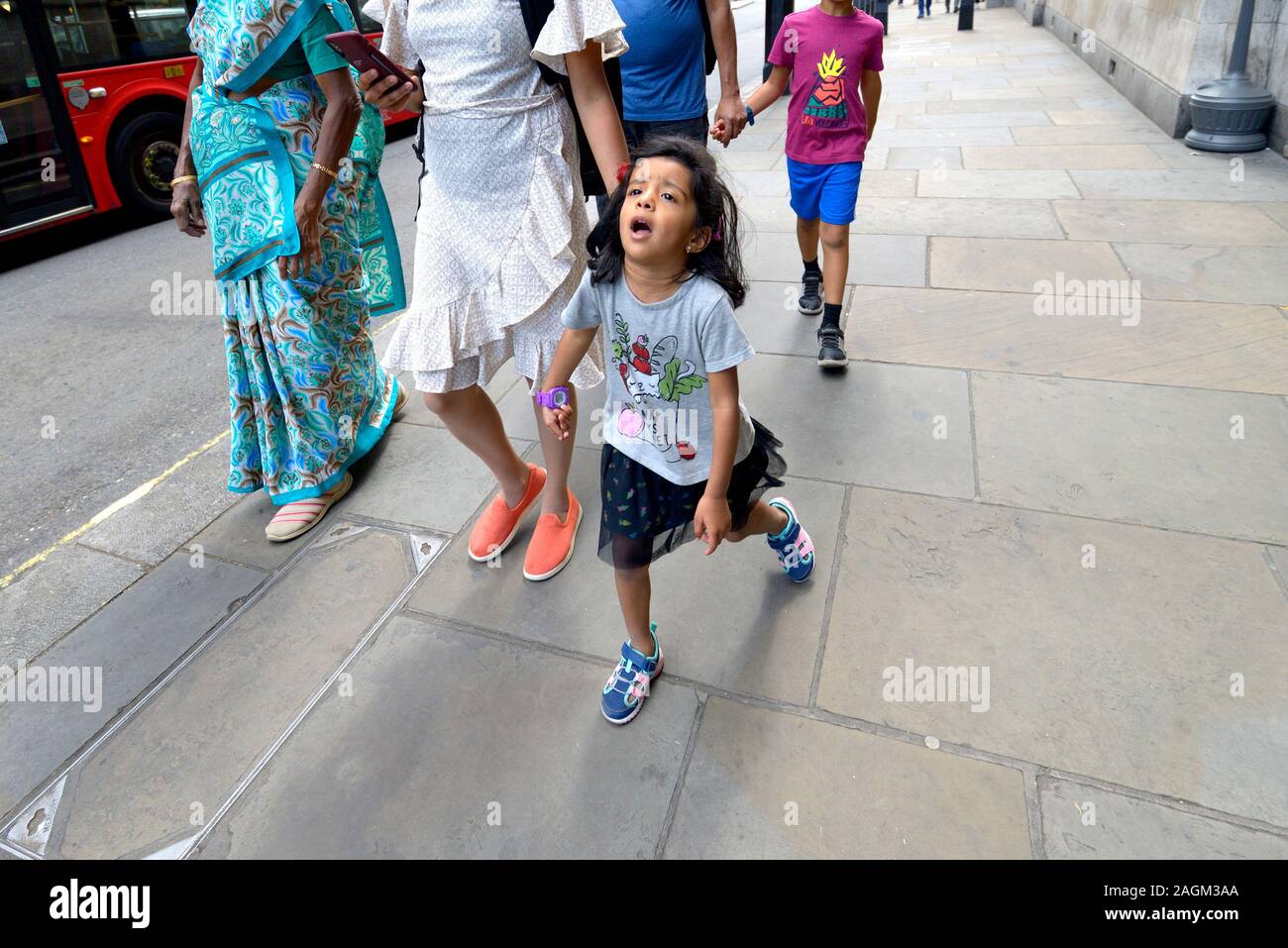 London, England, UK. Young girl walking, reluctantly, with her family Stock Photo