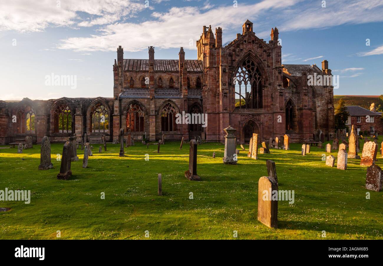 Melrose, Scotland, UK - May 28, 2011: Evening sun casts long shadows across the ruins of Melrose Abbey and gravestones in the abbey churchyard. Stock Photo