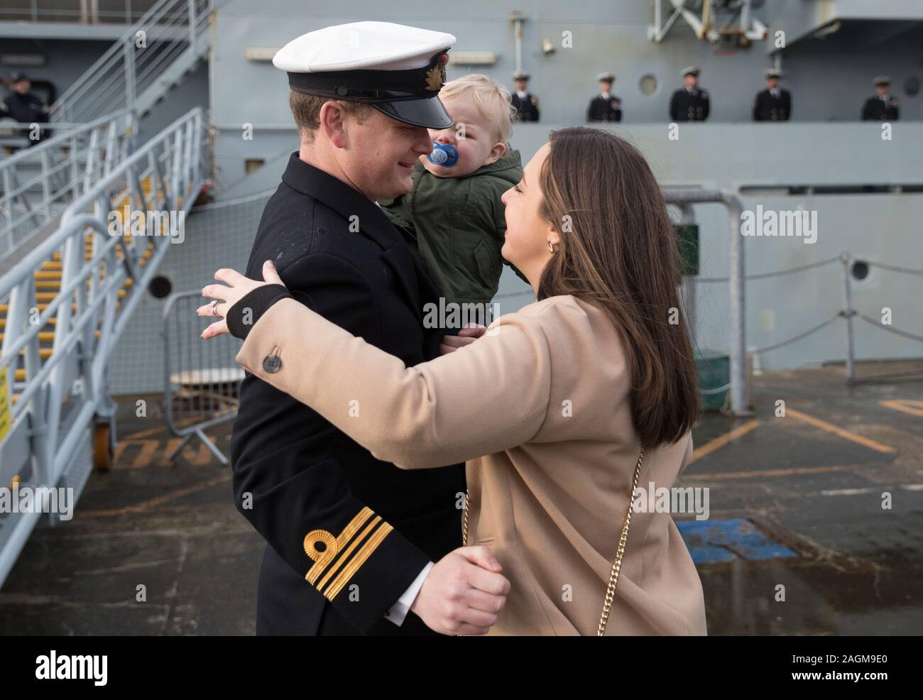 Lieutenant Commander Richard Skelton, Commanding Officer of HMS Clyde (left) embraces his wife Natalie and son Rory after he disembarked HMS Clyde following the ship's arrival back into Portsmouth for the first time in 12 years, ahead of her de-commissioning ceremony. Stock Photo