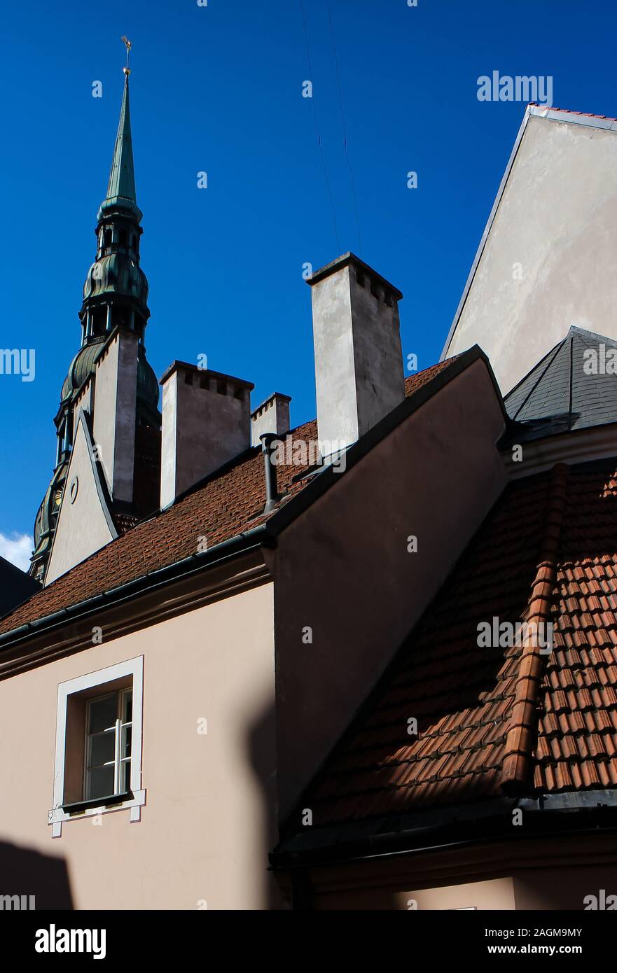 Street scene in Riga, Latvia, with the spire of St. Peter's Church visible behind residential buildings. Stock Photo