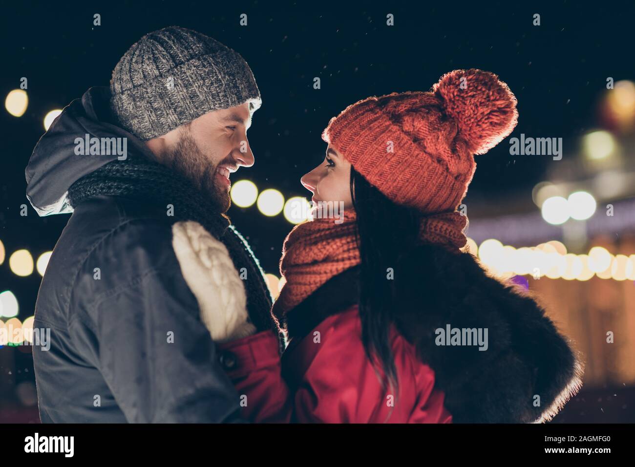 Photo of two affectionate people in love at midnight standing opposite looking eyes making newyear wish wearing warm jackets outside Stock Photo