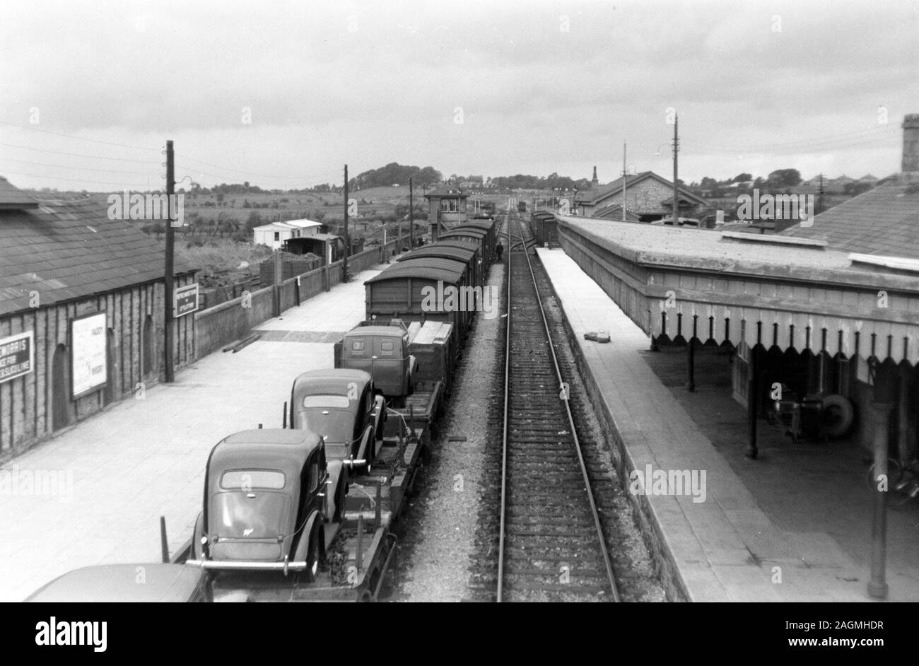 Historic monochrome photograph cars on goods train at railway station