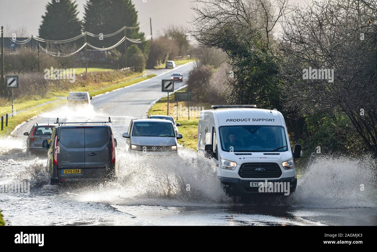 Brighton UK 20th December 2019 - Traffic drives through floodwater on the B2118 in the village of Albourne just north of Brighton in Sussex . The M23 has been closed in both directions after overnight flooding and heavy rain caused havoc with commuters and Christmas holiday travellers . Credit: Simon Dack / Alamy Live News Stock Photo