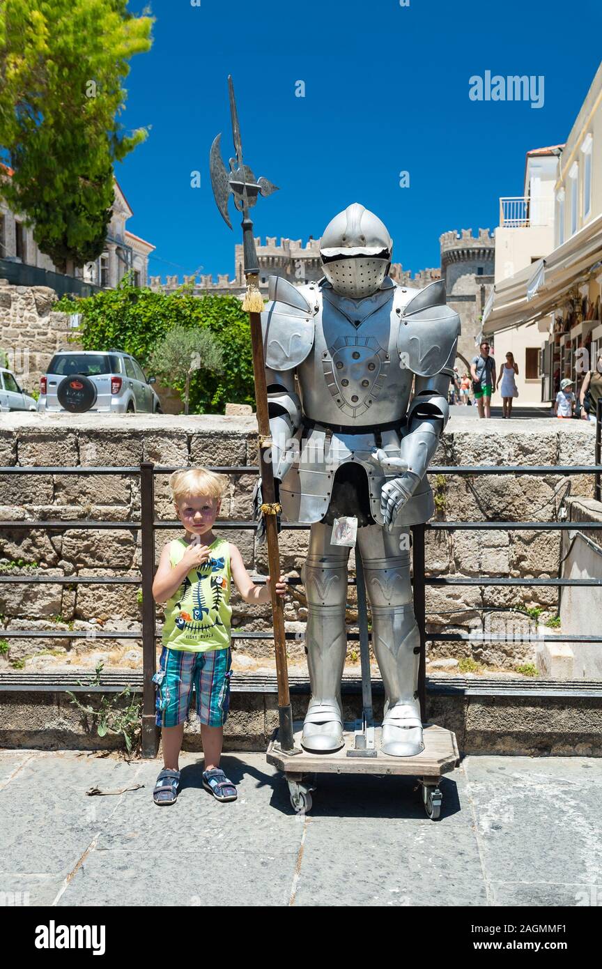 Three-year-old boy standing next to knight's armour on a street in Rhodes, Rhodes, Greece, Europe Stock Photo