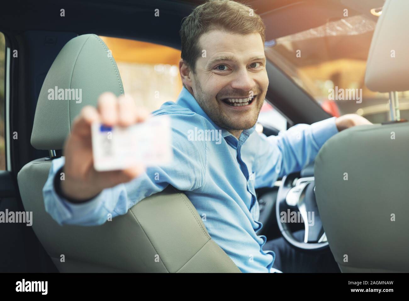 driving school - man sitting inside the car and showing his driver license Stock Photo