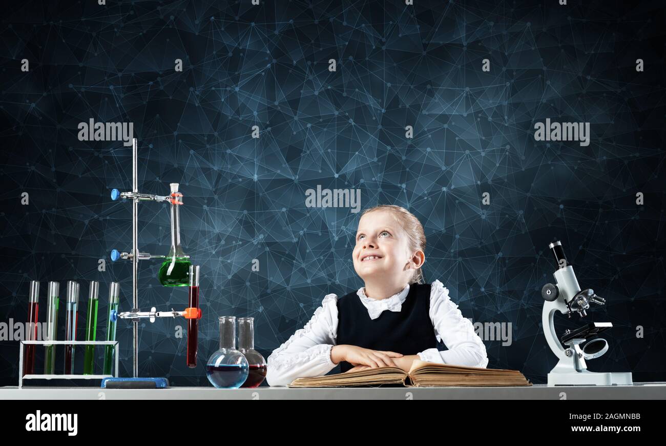 Smiling little girl sitting at desk with open book Stock Photo - Alamy