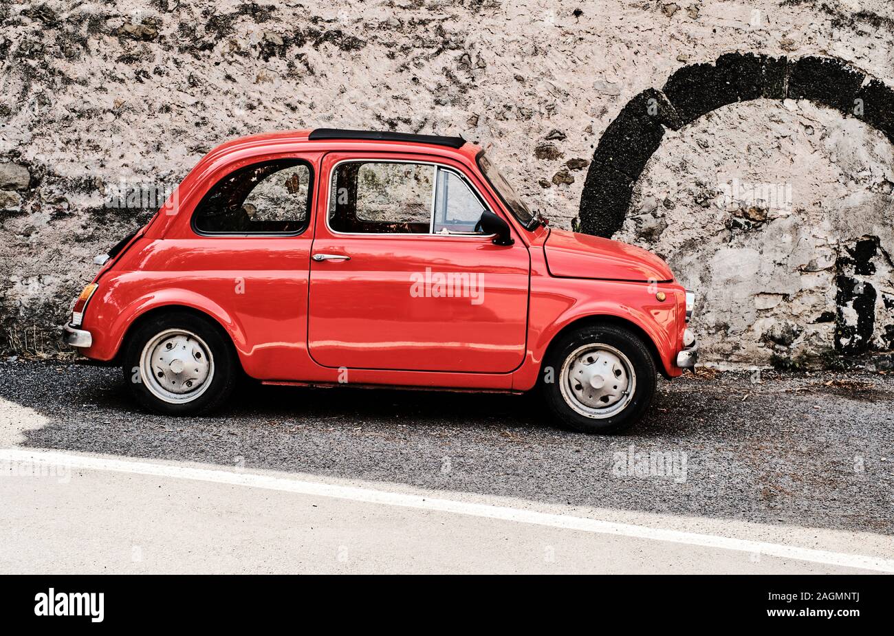 A bright red classic Fiat Cinque Cento / Fiat 500 parked in a street in Italy Stock Photo