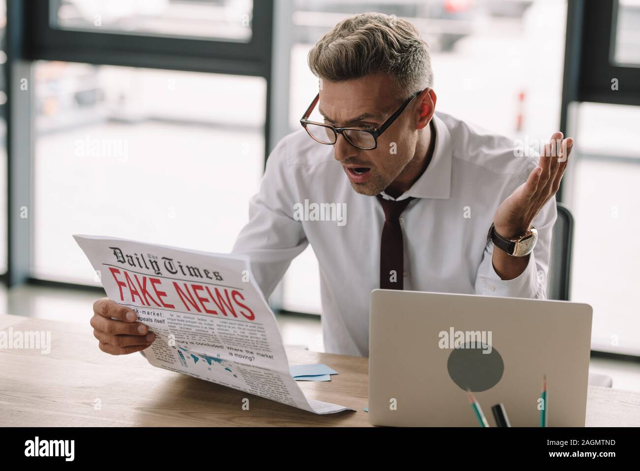 shocked businessman in glasses gesturing and reading newspaper with ...