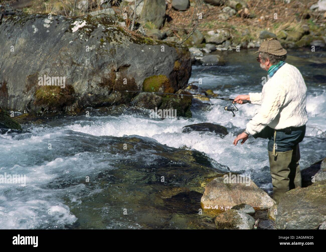 Countryside pursuits.Fishing.Man in country clothes.Deer stalker hat and waders. Fly fishing.a mountain stream. Hautes-Pyrenees.South-west France. Stock Photo