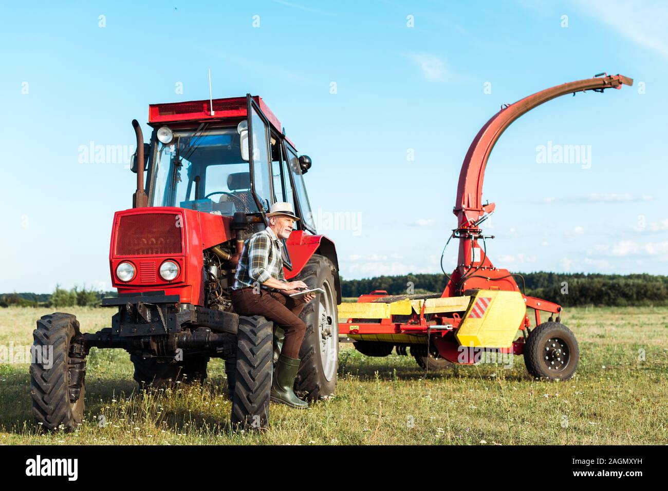 senior farmer using digital tablet near red tractor Stock Photo