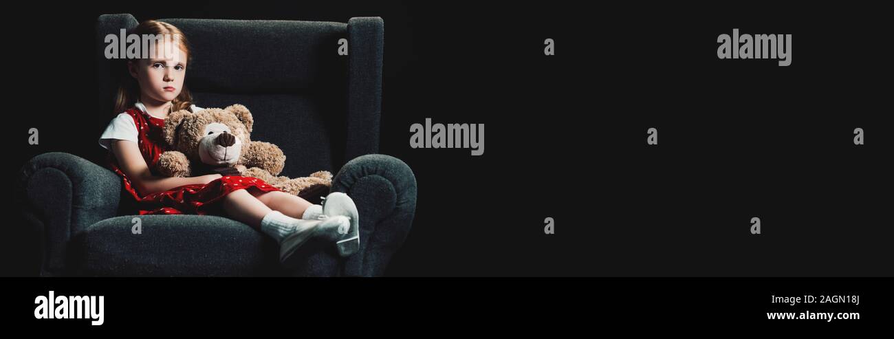 sad, lonely kid sitting in armchair with teddy bear and looking at ...
