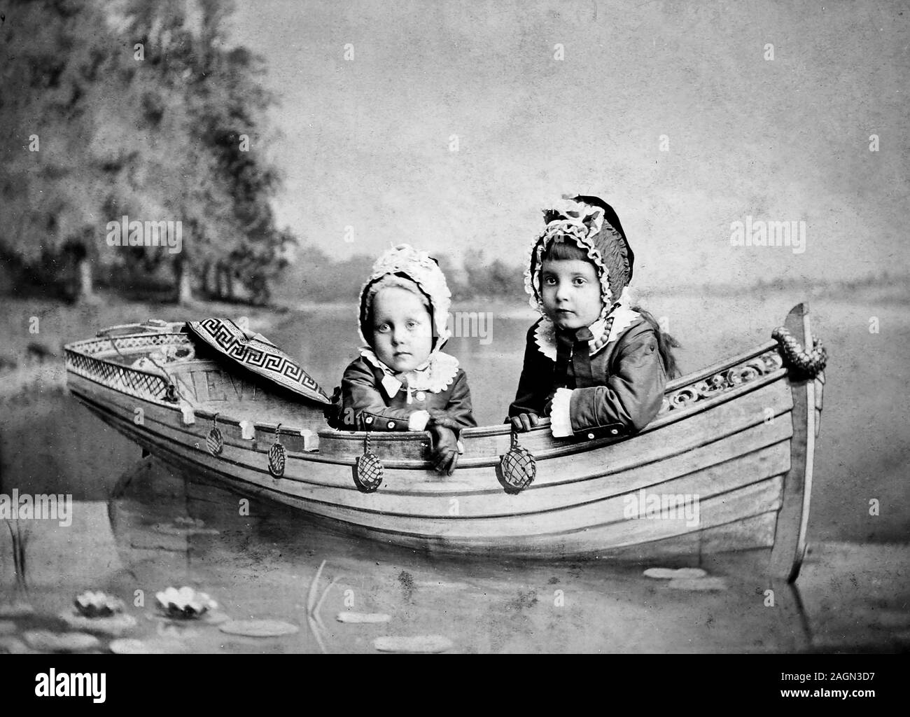 Two young children pose in a faux boat for a tintype portrait, ca. 1890. Stock Photo