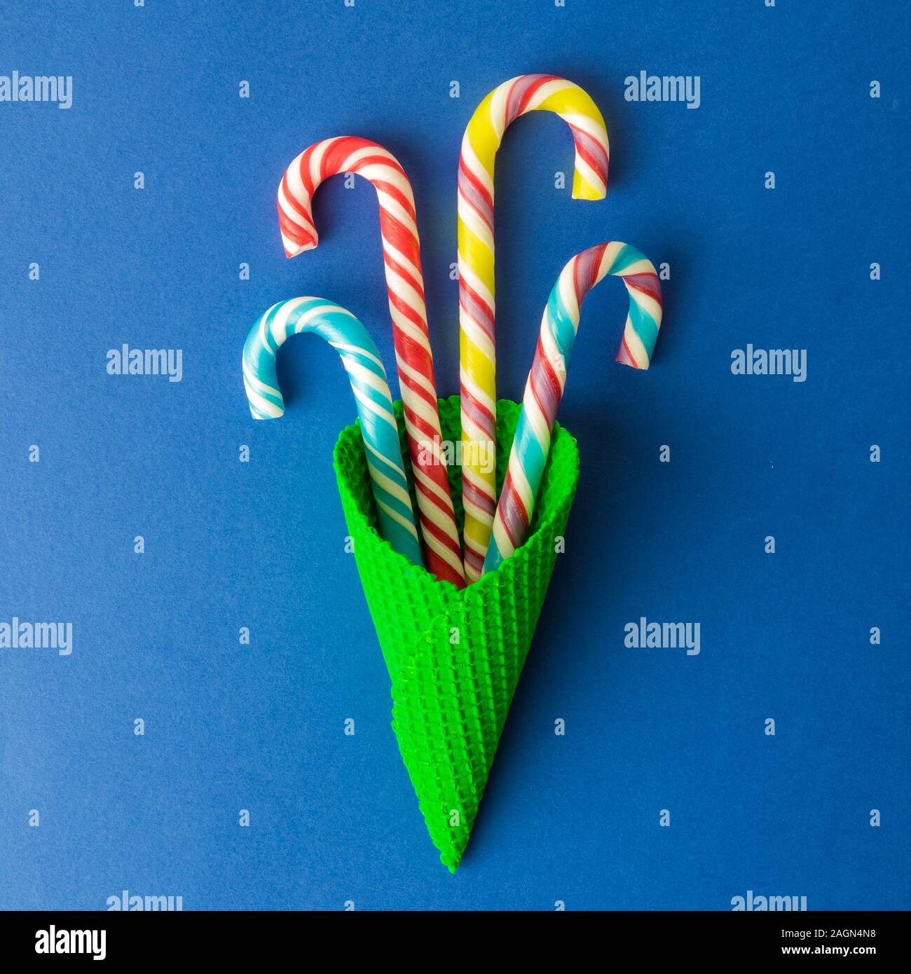 Flat lay of colorful candy canes in ice cream cone against classic blue