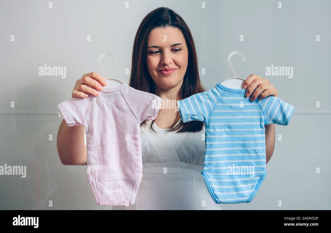 Pregnant choosing baby bodysuits Stock Photo