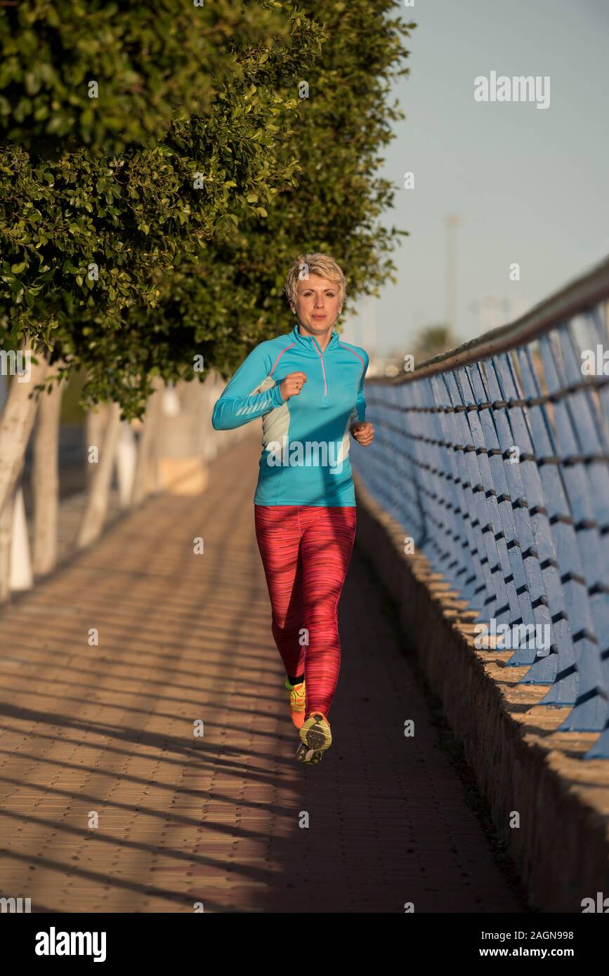 Female runner running down urban street, Alicante, Spain, Europe Stock Photo