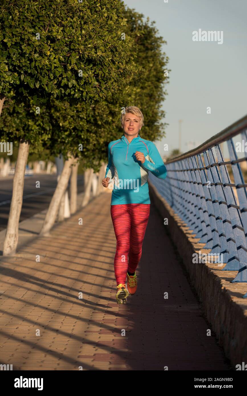 Female runner running down urban street, Alicante, Spain, Europe Stock Photo