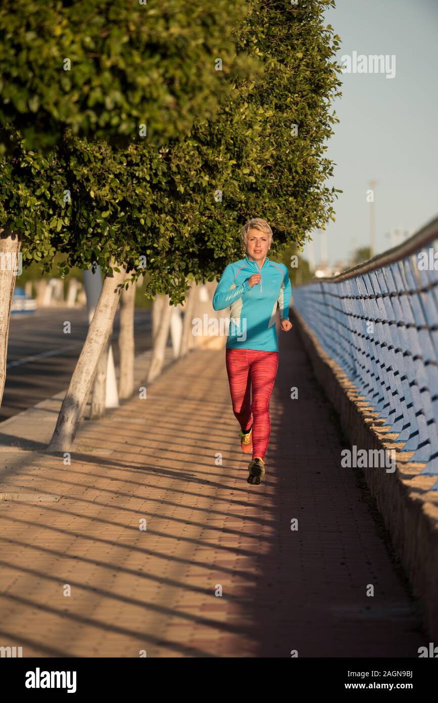 Female runner running down urban street, Alicante, Spain, Europe Stock Photo