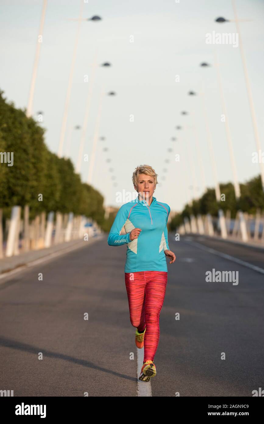 Female runner running down urban street, Alicante, Spain, Europe Stock Photo