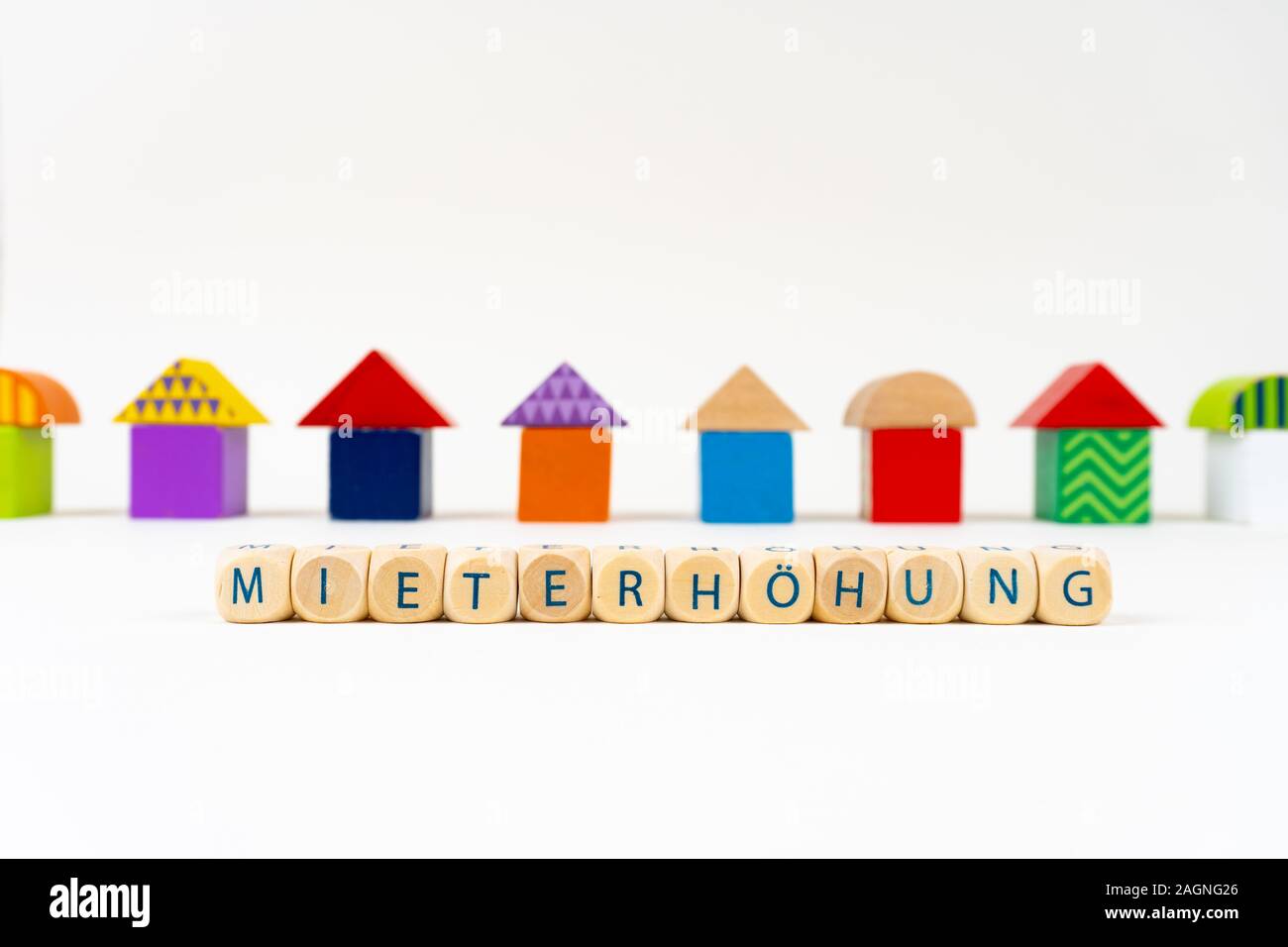 Wooden block with letters saying 'Mieterhöhung' (German for rent increase) in front of colorful toy houses Stock Photo