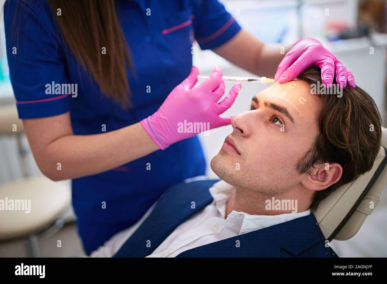 Male having aestetic intervention on his forhend in beauty salon Stock Photo
