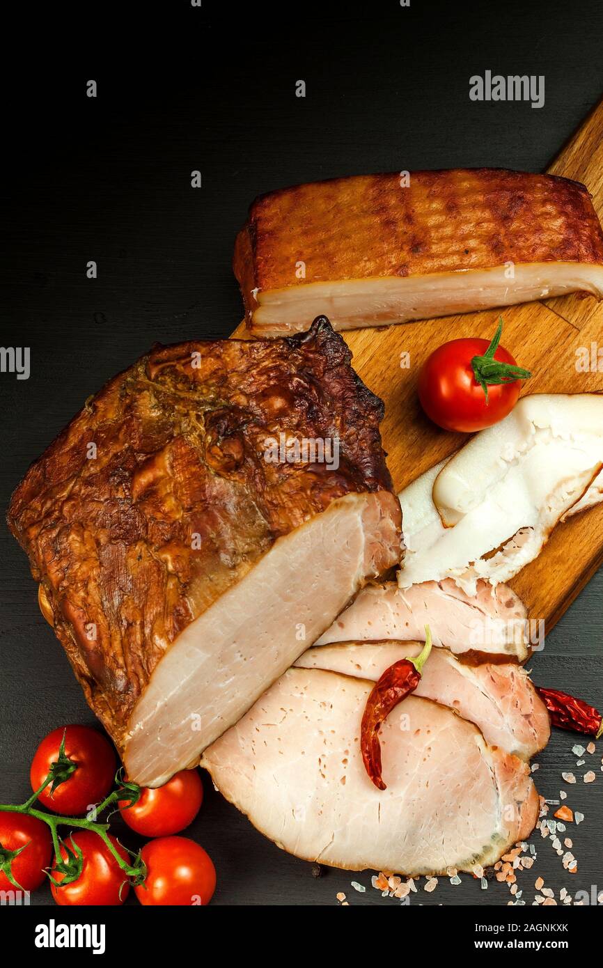 Smoked meat on a kitchen board. Homemade smoked pork with vegetables