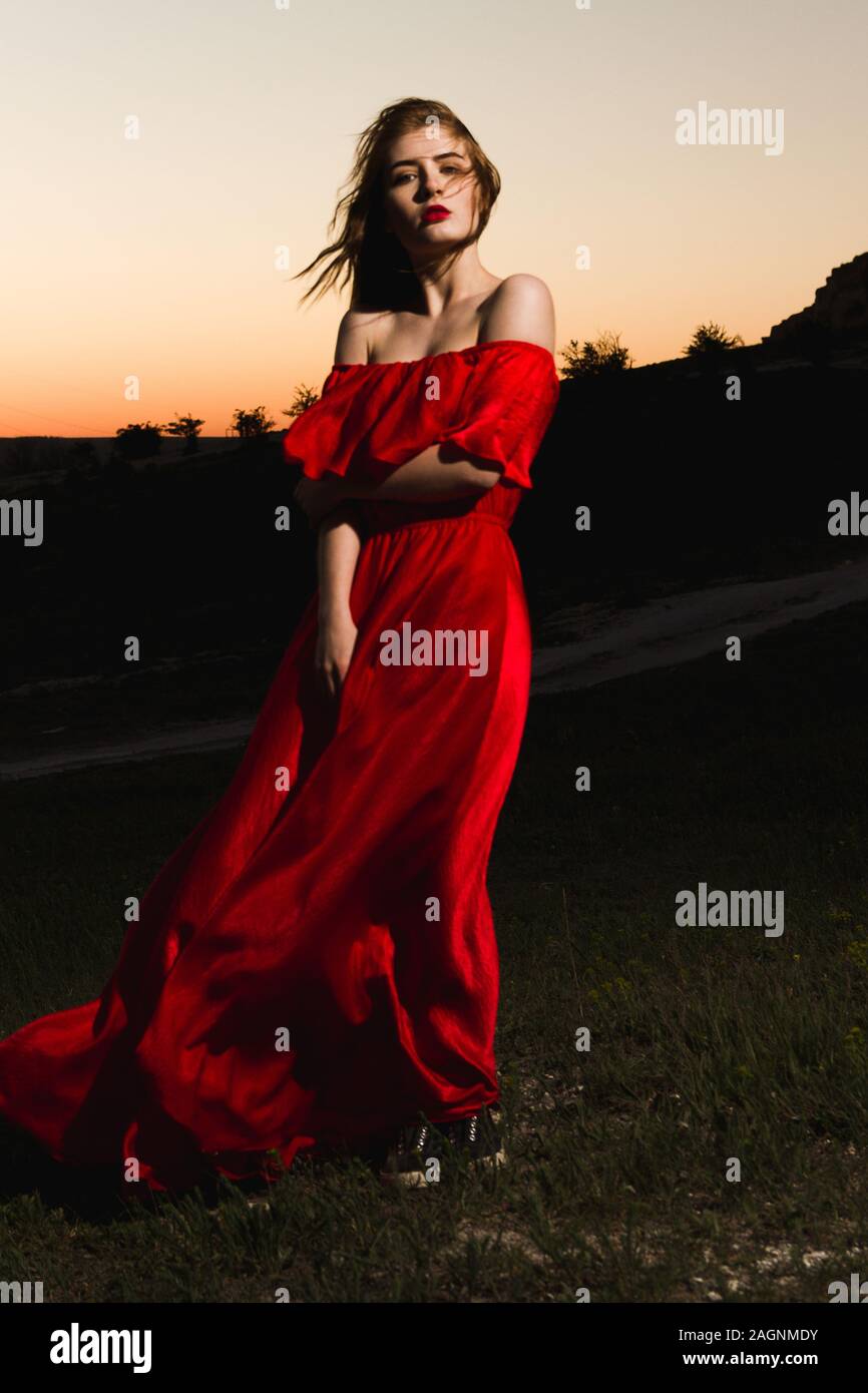 lovely young woman in a red silk dress on sunset background Stock Photo ...