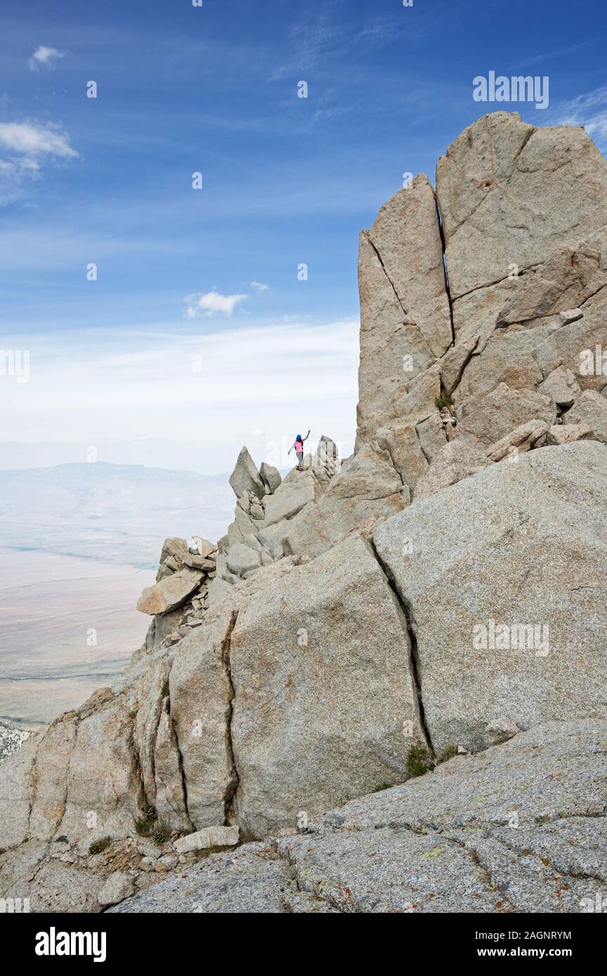 woman balances while scrambling up the north ridge of Lone Pine Peak Stock Photo