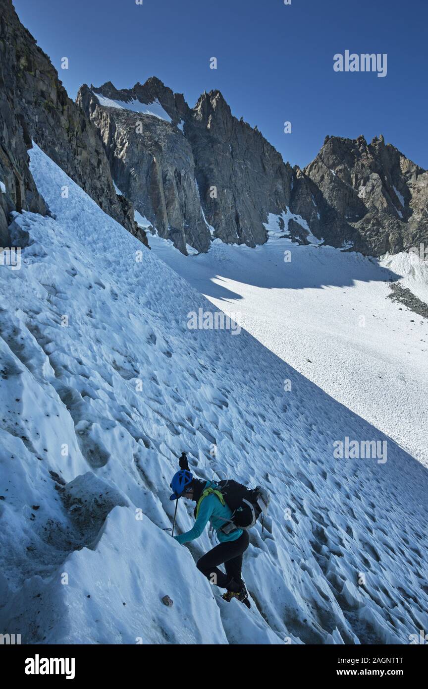 woman climbing up the North Palisade Glacier with North Palisade Peak above her Stock Photo