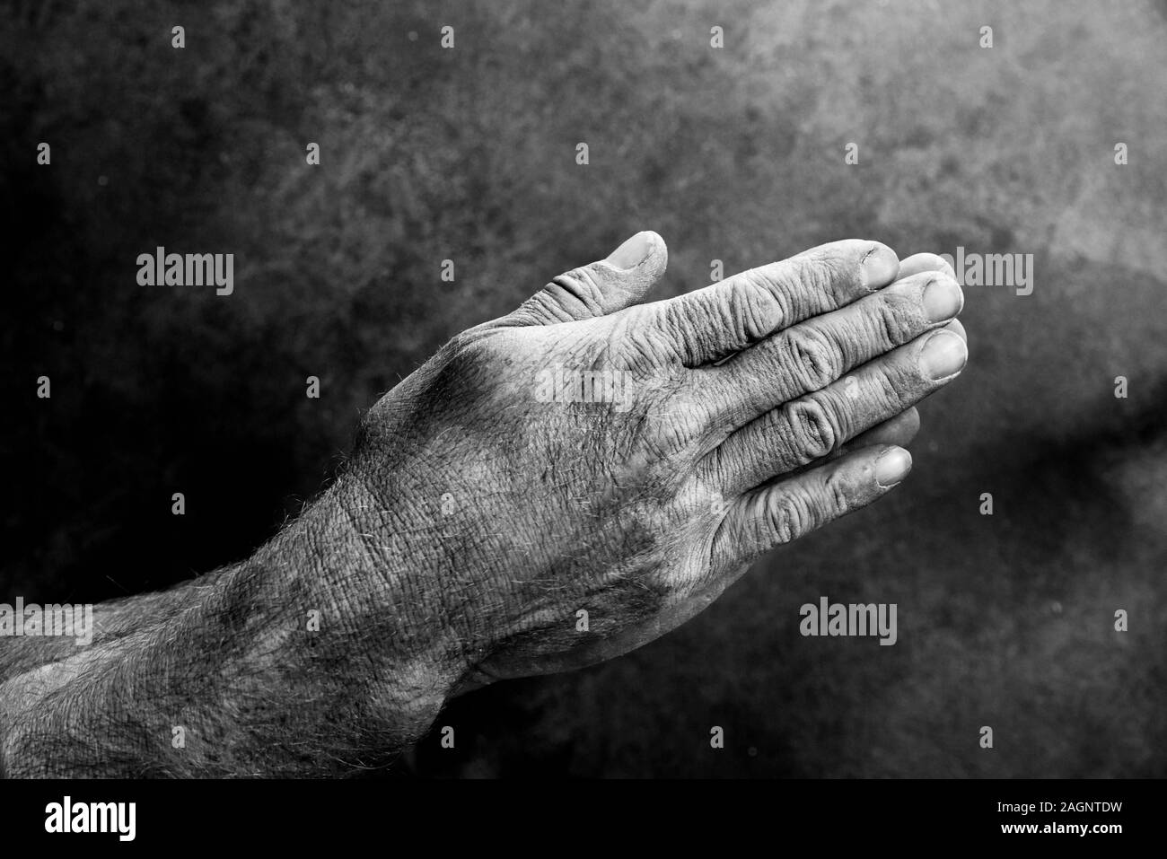 black and white image of a mans weathered hands held together in prayer Stock Photo
