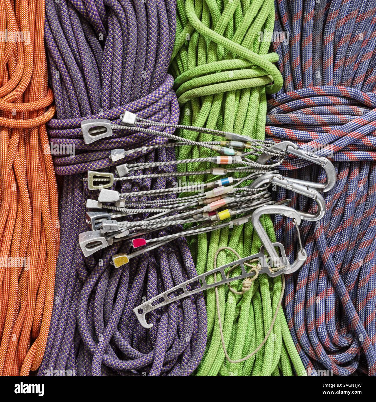 traditional rock climbing protection with used stoppers and nut tool and carabiners over a background of climbing ropes Stock Photo