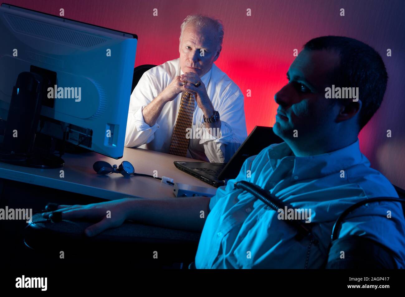 A polygraph examiner interviews a subject. A polygraph, popularly referred to as a lie detector test, is a device or procedure that measures and records several physiological indicators such as blood pressure, pulse, respiration, and skin conductivity while a person is asked and answers a series of questions. Stock Photo