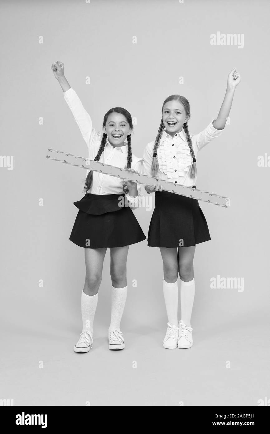 Measuring equipment. Kids students study math. Knowledge day. Schoolgirls school uniform hold big ruler. Geometry school lesson. Teamwork concept. Close or far. Measuring skills. Measuring distance. Stock Photo