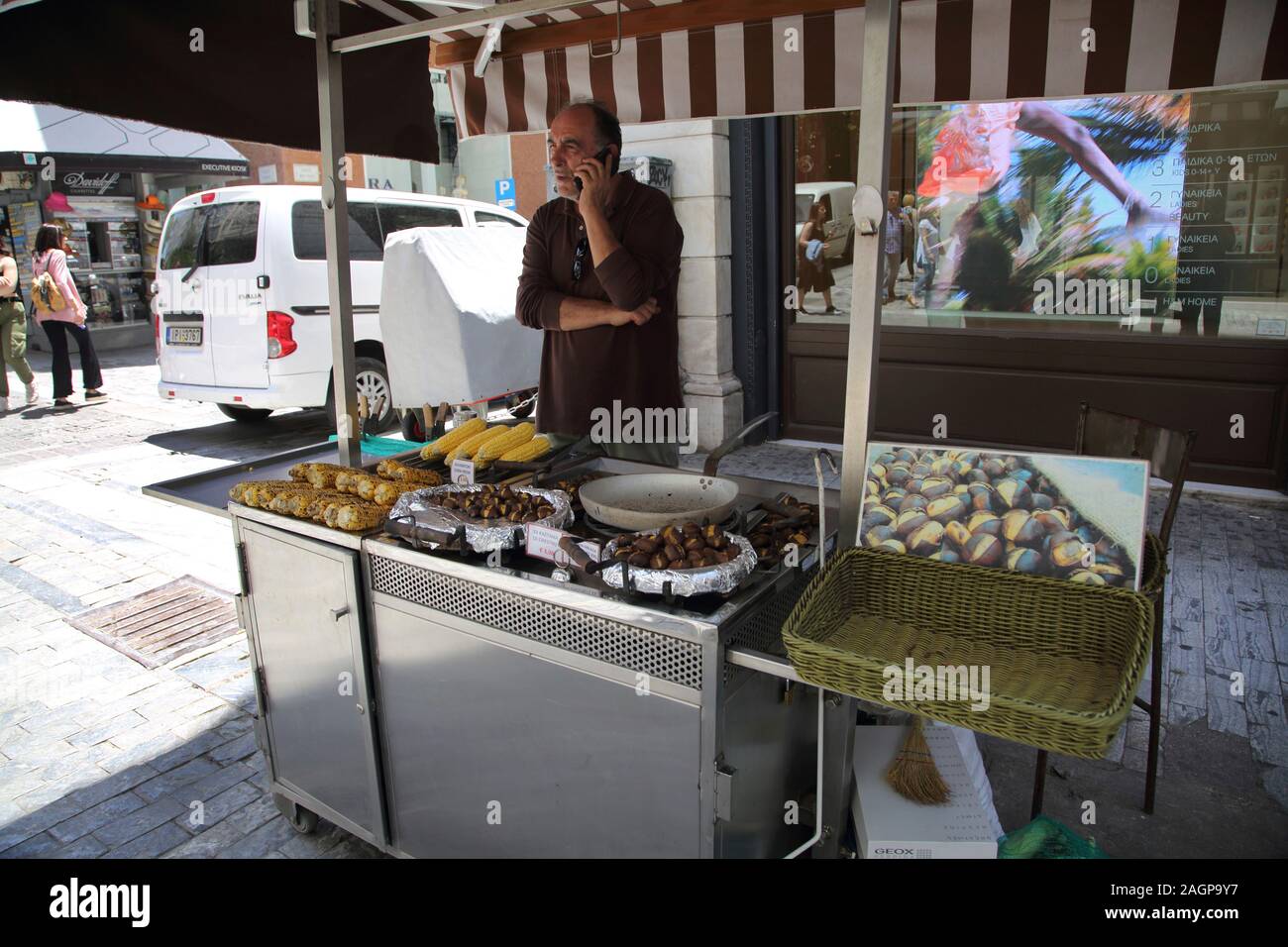 Athens Greece Ermou Street Sweetcorn and Roasted Chestnut Stall - Stallholder on Mobile Phone Stock Photo