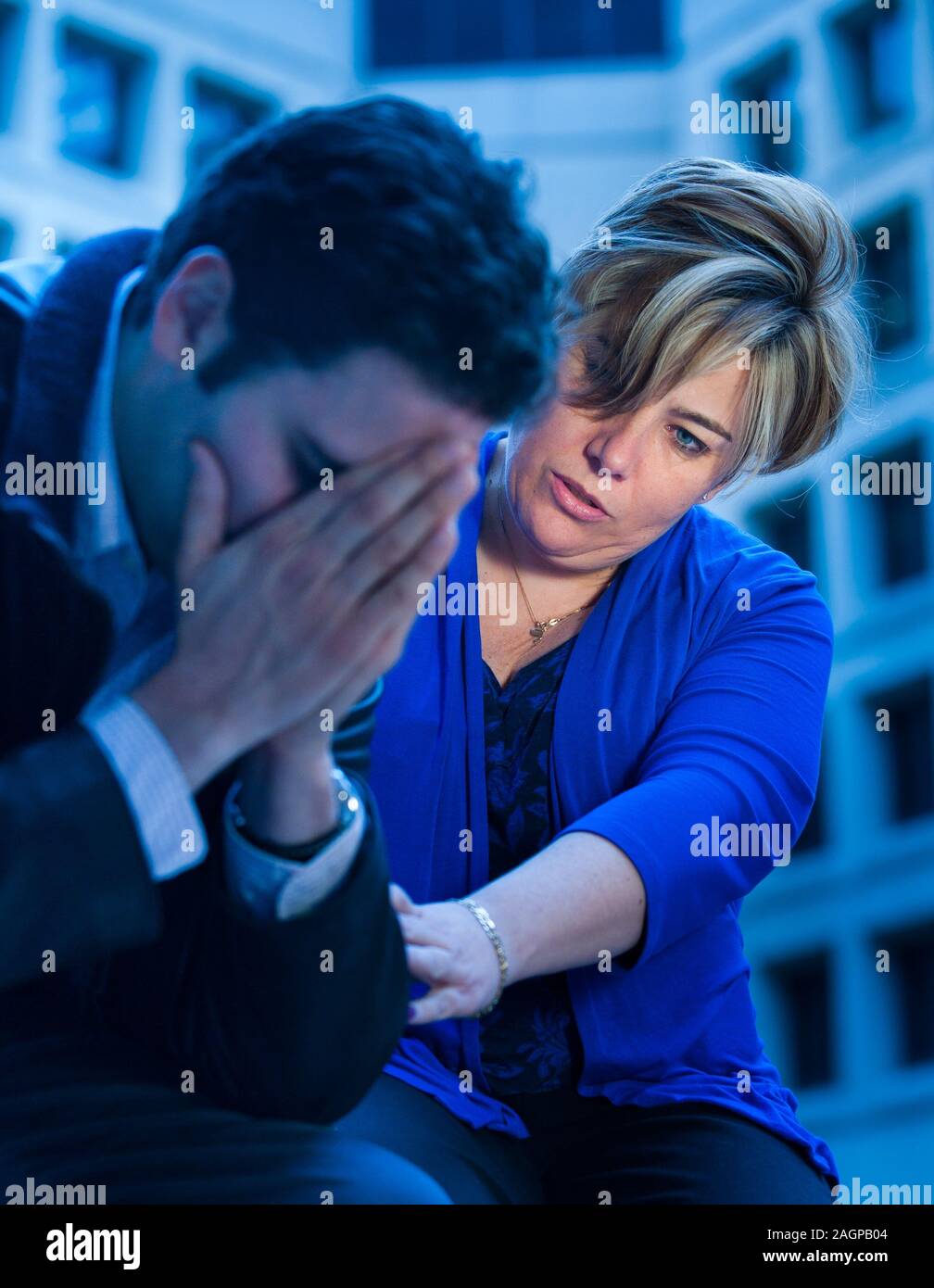 A woman comforts a grieving man. Stock Photo