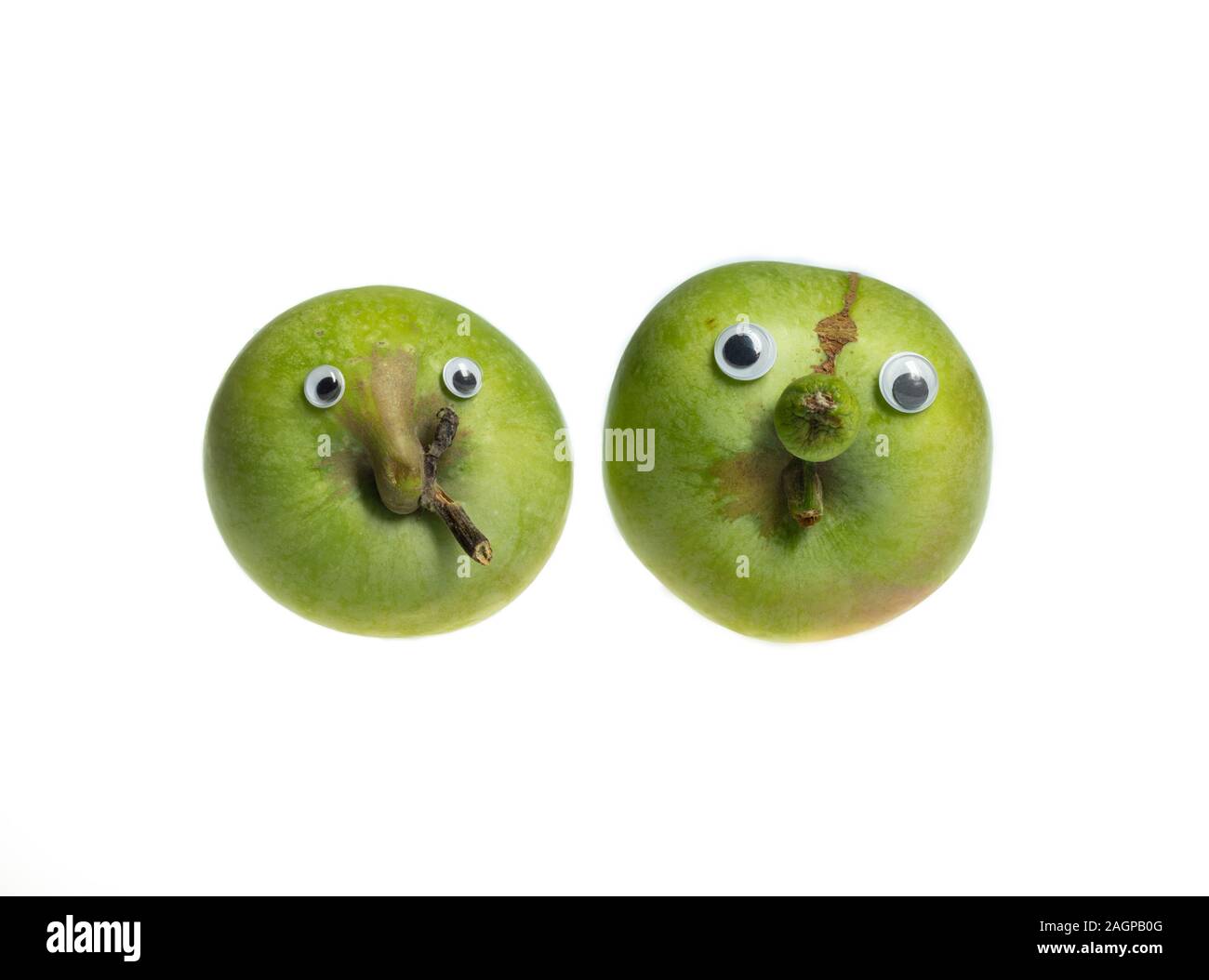 Trendy ugly food concept. Two green funny apples with eyes isolated on