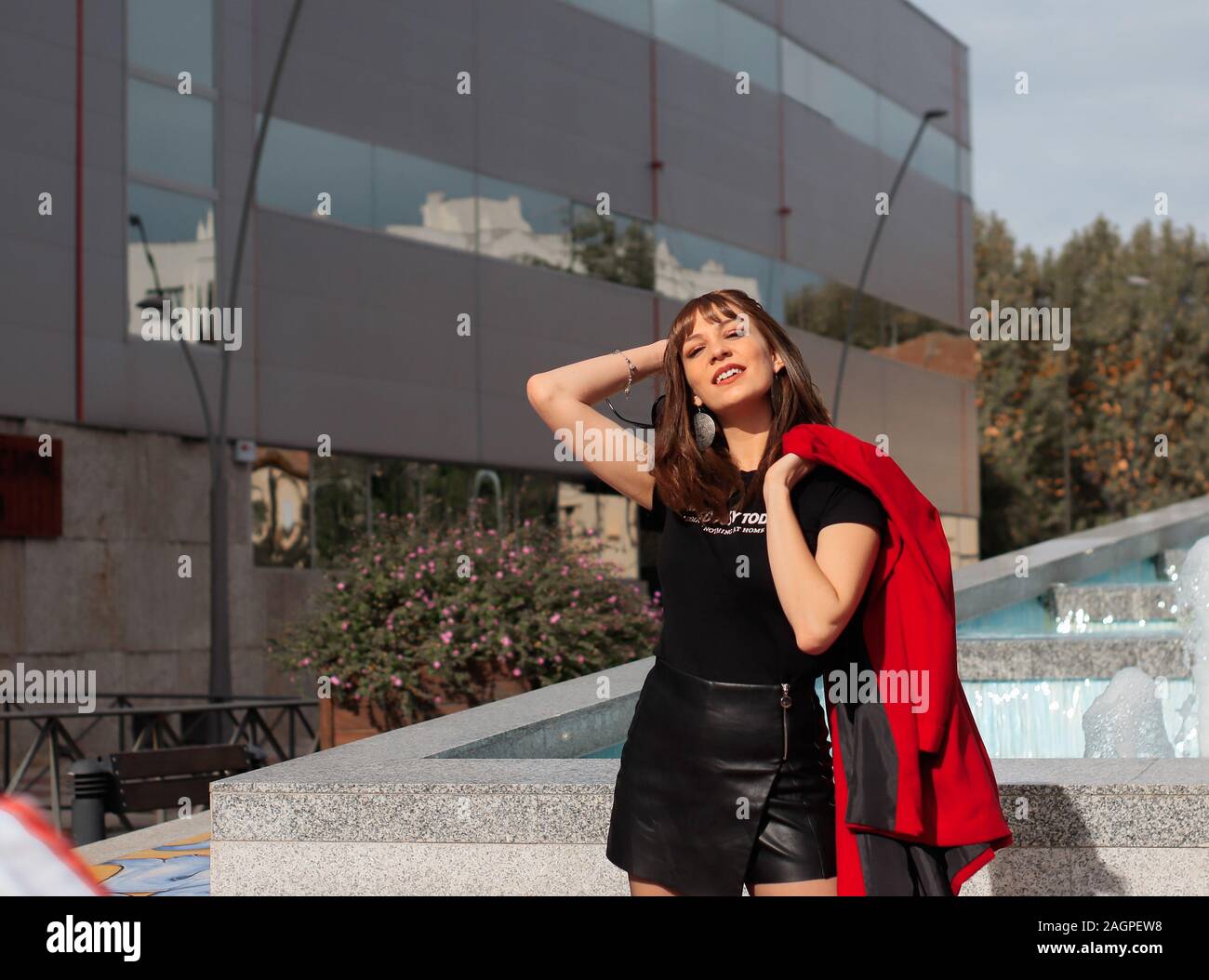 Beautiful young woman with red jacket smiling and enjoying in the city Stock Photo
