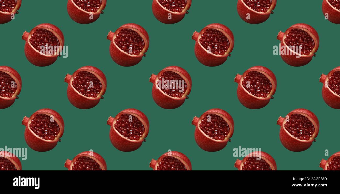 Pomegranate pattern on a green background. Summer fruit seamless pattern. Original minimal food concept. Pomegranate fruit with red shiny beads. Stock Photo