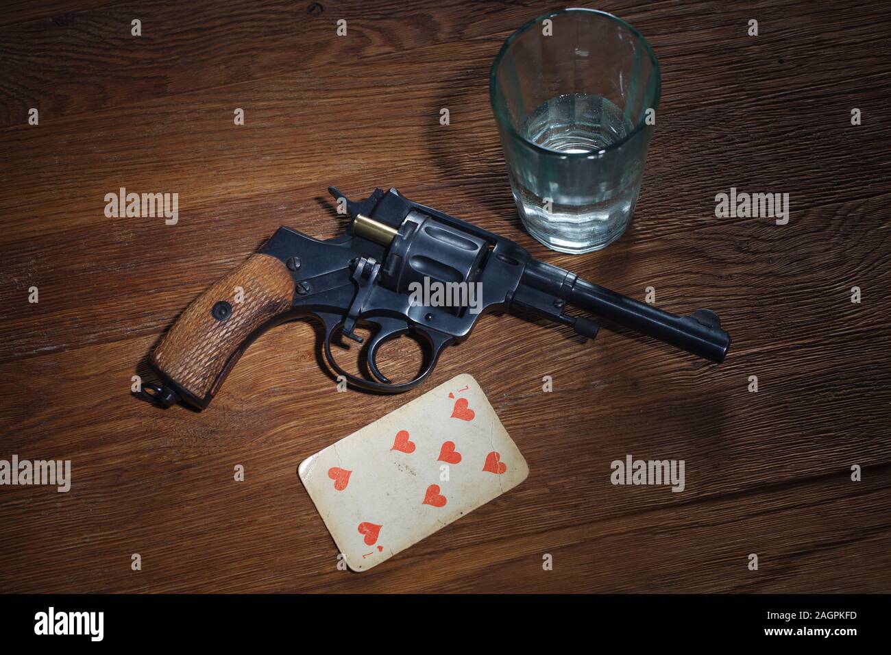 An old metal pistol with a drum on a wooden table.Russian roulette. A  revolver . Stock Photo