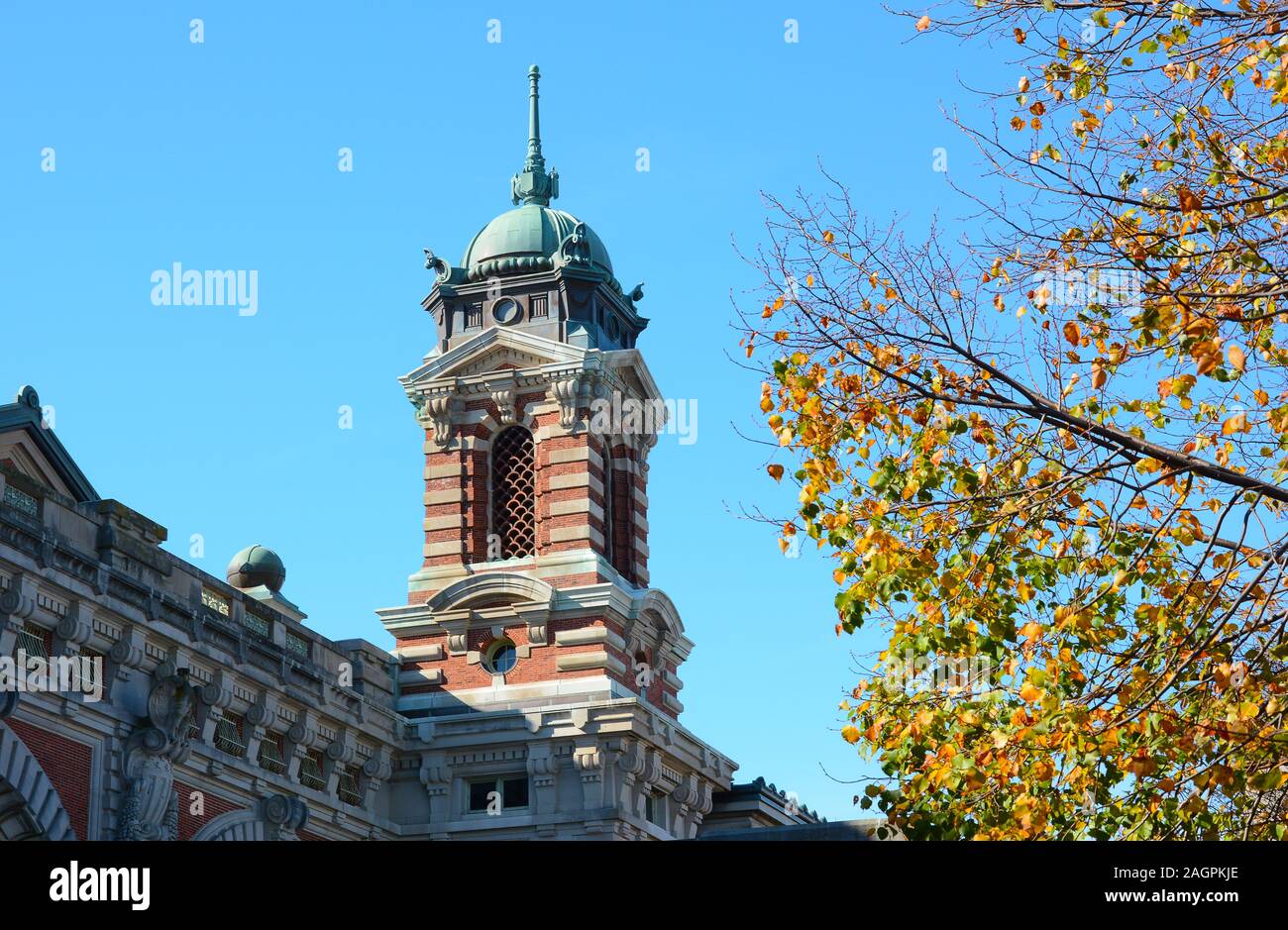 NEW YORK, NY - 04 NOV 2019: Closeup of a tower atop the National Museum of Immigration at Ellis Island with fall foliage. Stock Photo