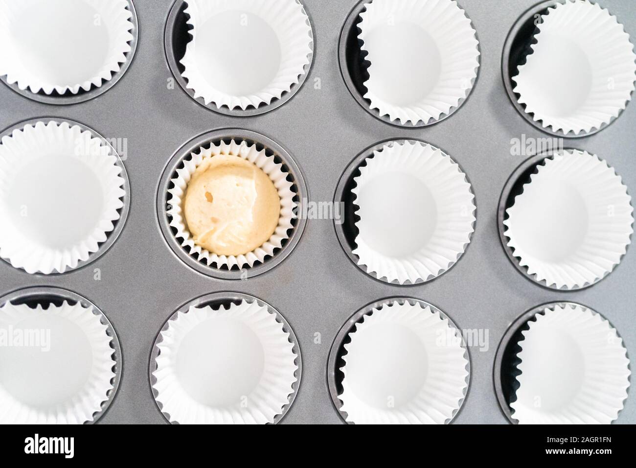https://c8.alamy.com/comp/2AGR1FN/scooping-cupcake-batter-into-cupcake-pan-lined-with-cupcake-liners-to-bake-vanilla-cupcakes-2AGR1FN.jpg