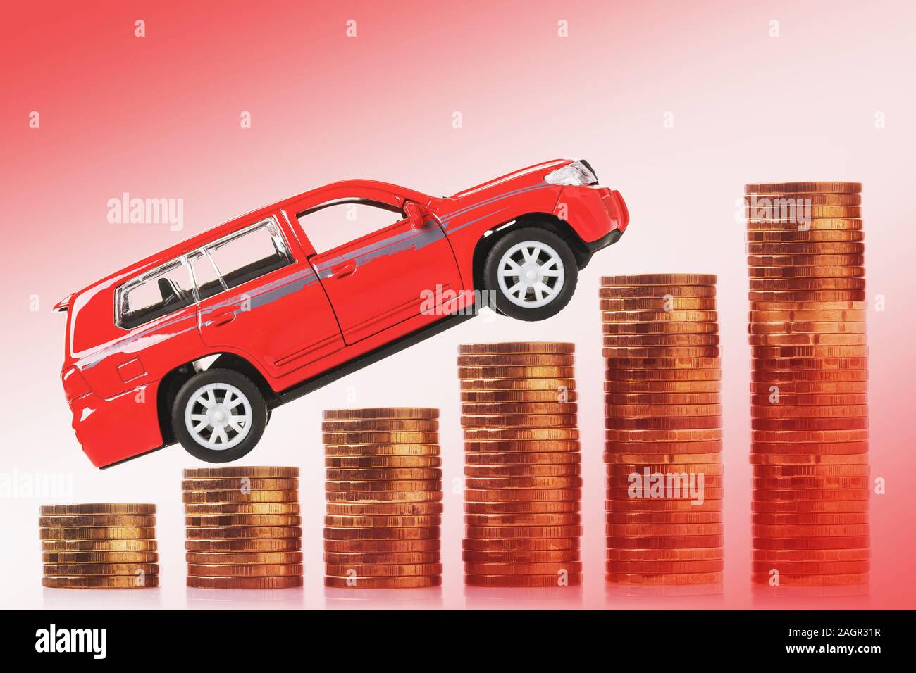 Toy car on a background of coins. Concept on the theme of rising transport tax. Stock Photo