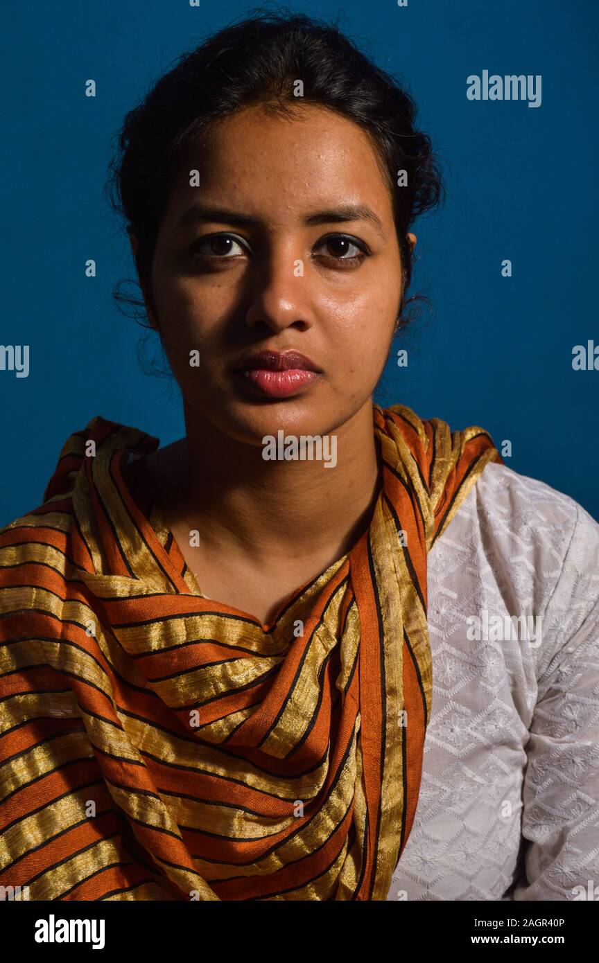 A student posing like sitter, model at classroom for portfolio with rembrandt lighting system with blue background. Stock Photo