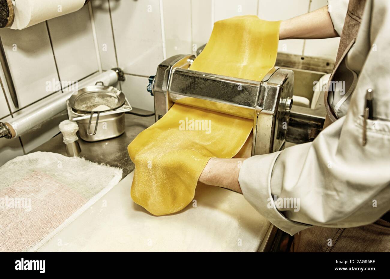 Chef is making thin dough with special machine, toned image Stock Photo