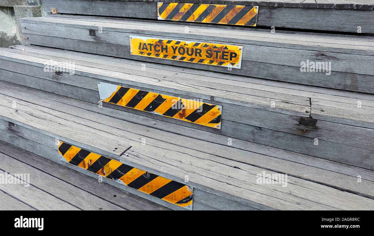 Wooden steps with caution sign of 'watch your step' and some others with yellow and black stripes. Stock Photo