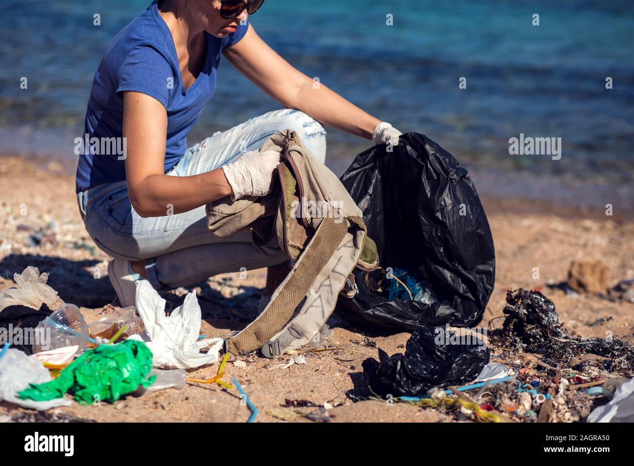Woman volunteer with black bag collect garbage on the beach. Environmental pollution concept Stock Photo