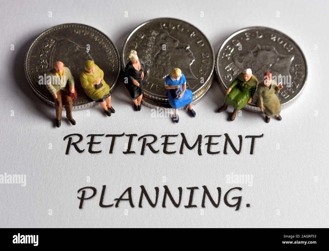 People sitting on coins behind the word retirement planning Stock Photo