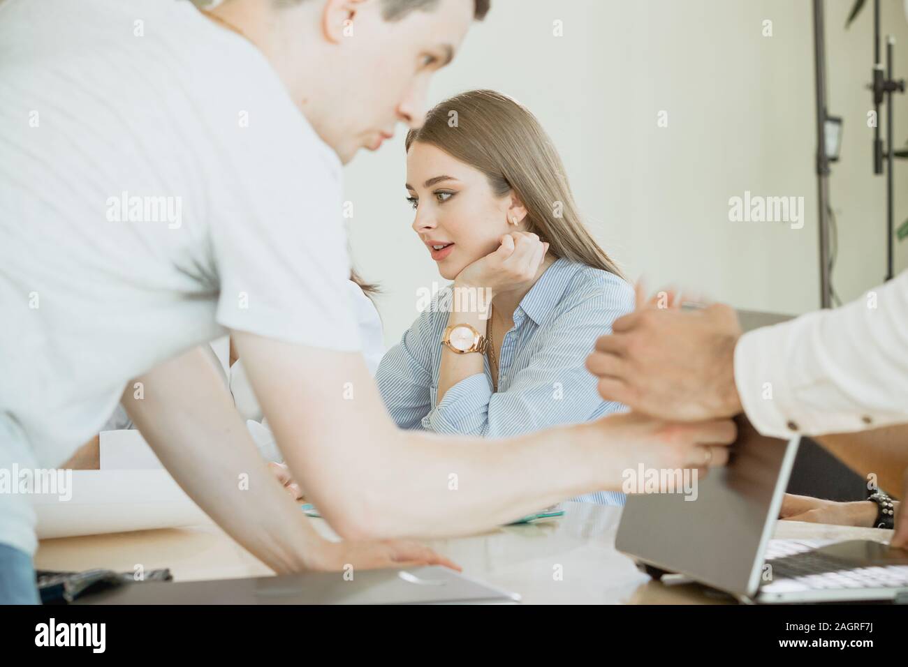 Involvement in the workflow. A young female employee is busy with work and is not distracted by the noise and work of other colleagues. Stock Photo