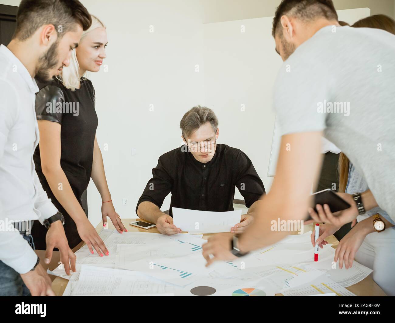 The company of young employees at a meeting with the project manager offer their options for project implementation Stock Photo